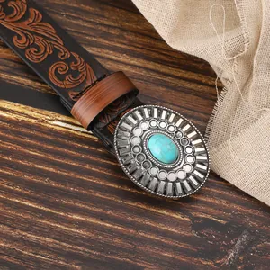 Detail of vintage black PU leather belt featuring floral embossing and turquoise buckle