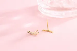 Close-up of curved gold S925 silver stud earrings with sparkling cubic zirconia stones