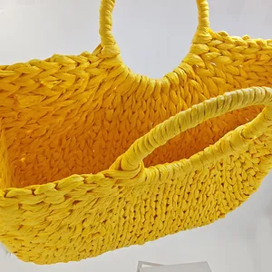 Bright yellow handmade woven straw handbag with crescent moon shape for beach vacations