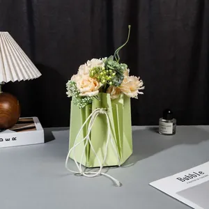 Détail d'un sac floral vert clair avec des roses champagne et un cordon blanc