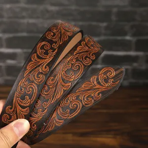 Close-up of vintage brown leather belt with embossed floral patterns and western style