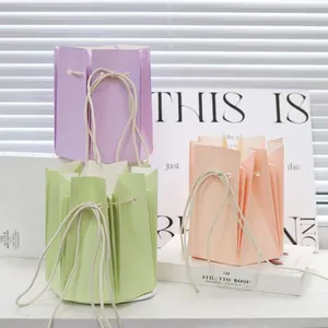 Trois sacs cadeaux plissés en violet, vert et rose avec anses en coton pour fleurs