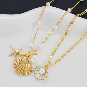 Detailed close-up of golden sea star and shell charms with pearls on a flat snake chain