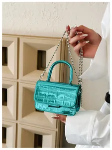 Detail of teal crocodile pattern mini bag with silver bead chain and top handle