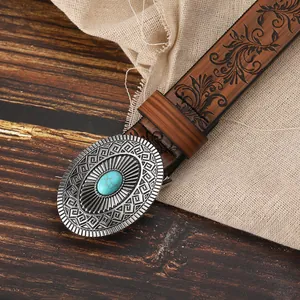 Detail of western leather belt showing embossed floral patterns and turquoise buckle