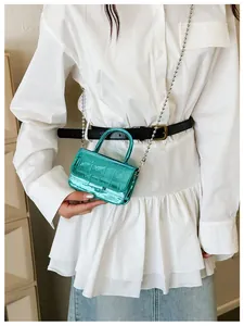 Close-up of metallic green crocodile pattern girls mini bag with silver bead chain strap