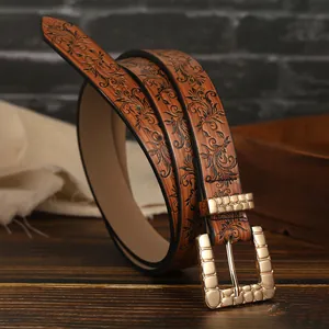 Detailed macro view of vintage brown leather belt with embossed floral texture and gold buckle