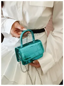 Detailed macro of green mini handbag with metallic crocodile texture and silver bead chain
