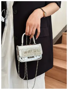Detail of mini silver laser crossbody bag with crocodile pattern and silver bead chain