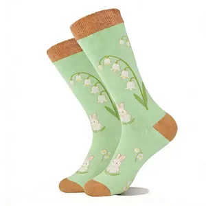Close-up of mint green crew socks with white rabbit and lily of the valley floral patterns