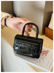 Detail of black faux crocodile patent leather mini bag with silver ball chain strap