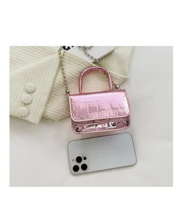 Mini metallic pink purse with crocodile pattern shown next to a phone for size scale