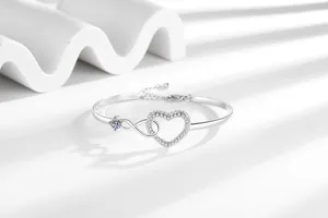 Detailed macro of silver infinity heart bracelet with cubic zirconia and adjustable chain