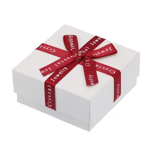 Macro detail of white jewelry gift box with textured finish and red silk ribbon accent