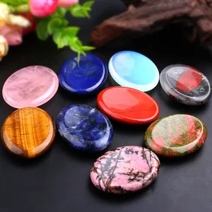 Close-up of polished oval natural healing gemstones in various colors on black surface