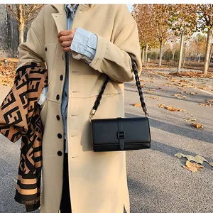 Détail d'un sac à rabat en cuir noir avec bandoulière tressée et fermoir métallique