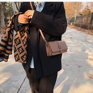 Détail d'un sac bandoulière marron vintage avec boucle carrée et texture en cuir mat