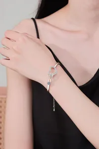 Close-up of infinity heart bracelet with zircons and blue stone on female wrist
