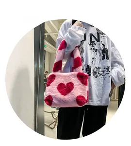 Détail d'un sac en peluche rose avec motif cœur rouge et poignée rayée colorée