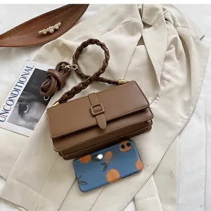 Détail du sac vintage en cuir marron avec poignée tressée et boucle carrée élégante