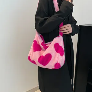 Sac fourre-tout en peluche rose à motifs cœurs rouges porté par un mannequin en manteau