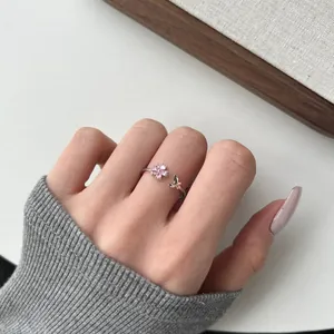 S925 sterling silver ring detail with pink flower, butterfly accent and open band on finger