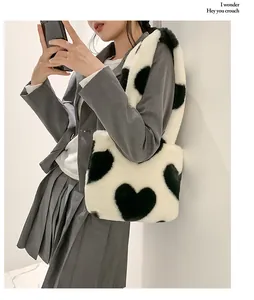 Détail du sac cabas en peluche blanc avec motifs de cœurs noirs porté sur une tenue grise