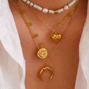 Primer plano de collares de capas en oro de 14K y acero con circón verde y colgantes luna