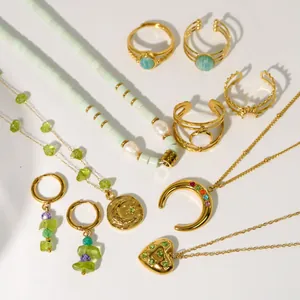Conjunto de collares dorados con piedras verdes, anillos y pendientes sobre fondo blanco
