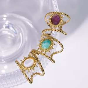 Vintage gold sunflower rings with turquoise, purple, and pearl stones on glass rim
