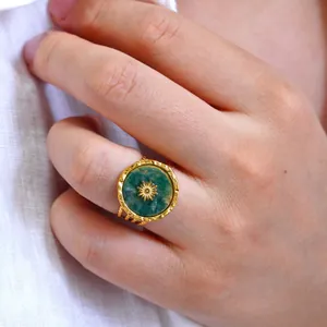Gros plan d'une bague large vintage avec pierre verte et motif étoile au doigt