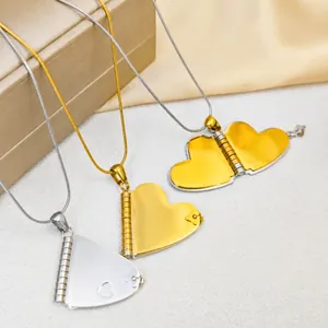 Detail of opening heart locket pendant in gold and silver finish with snake chain