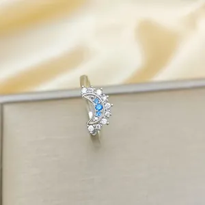 Elegant silver crescent moon ring with blue gemstones and white zircons on silk background