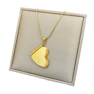 Gold heart-shaped locket necklace on beige jewelry display with a sleek snake chain