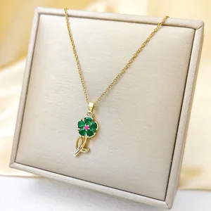 Macro detail of golden flower pendant with green heart gems on gray jewelry box