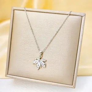 Macro shot of silver maple leaf pendant with clear zircons on champagne jewelry box