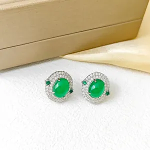 Gros plan de boucles d'oreilles vintage en argent avec pierres vert émeraude et diamants