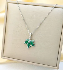 Detailed view of maple leaf pendant with green crystals on a premium jewelry stand