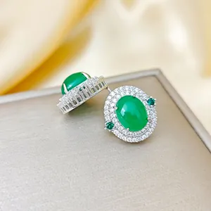 Détail de boucles d'oreilles émeraude serties de zircons blancs sur fond de soie