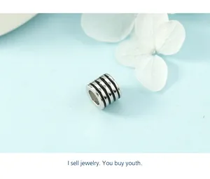 Detailed macro view of minimalist silver cylinder charm with black enamel stripe accents