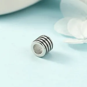 Minimalist silver cylinder pendant with black stripes on a fresh blue background