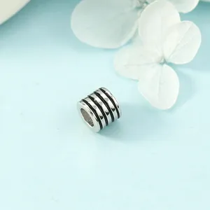 Minimalist silver cylinder necklace pendant with black enamel stripes on blue petals background