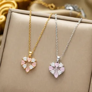 Detail of gold and silver heart pendants featuring pink cat's eye stone and zircon crystals