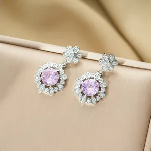 Détail de boucles d'oreilles iris rose avec zircon sur une boîte à bijoux or champagne
