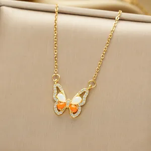 Macro detail of gold butterfly pendant with orange and white teardrop stones and diamonds