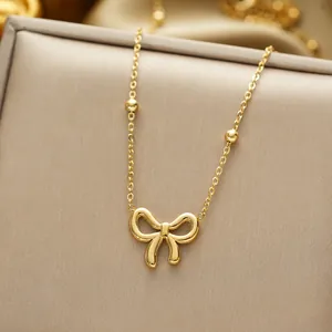 Polished titanium steel bow pendant necklace with beaded chain on jewelry box
