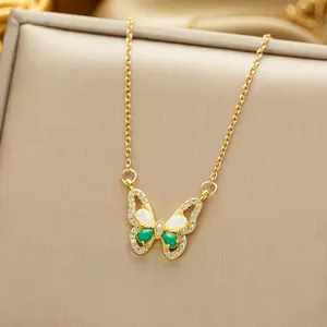 Macro shot of gold butterfly pendant with green and white gems on beige box