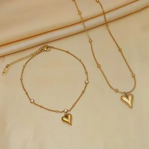 Elegant gold titanium steel heart necklace and bracelet set with crystal accents on satin