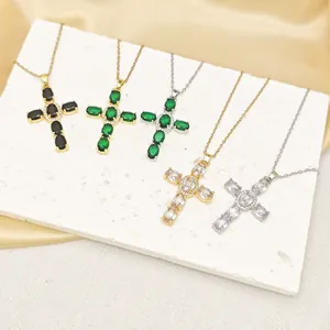 Detail of colorful zircon cross necklaces in multiple gems on white marble and silk