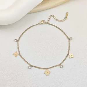 Detail of gold clover bracelet with zircons and S.Steel stamp on a white satin background